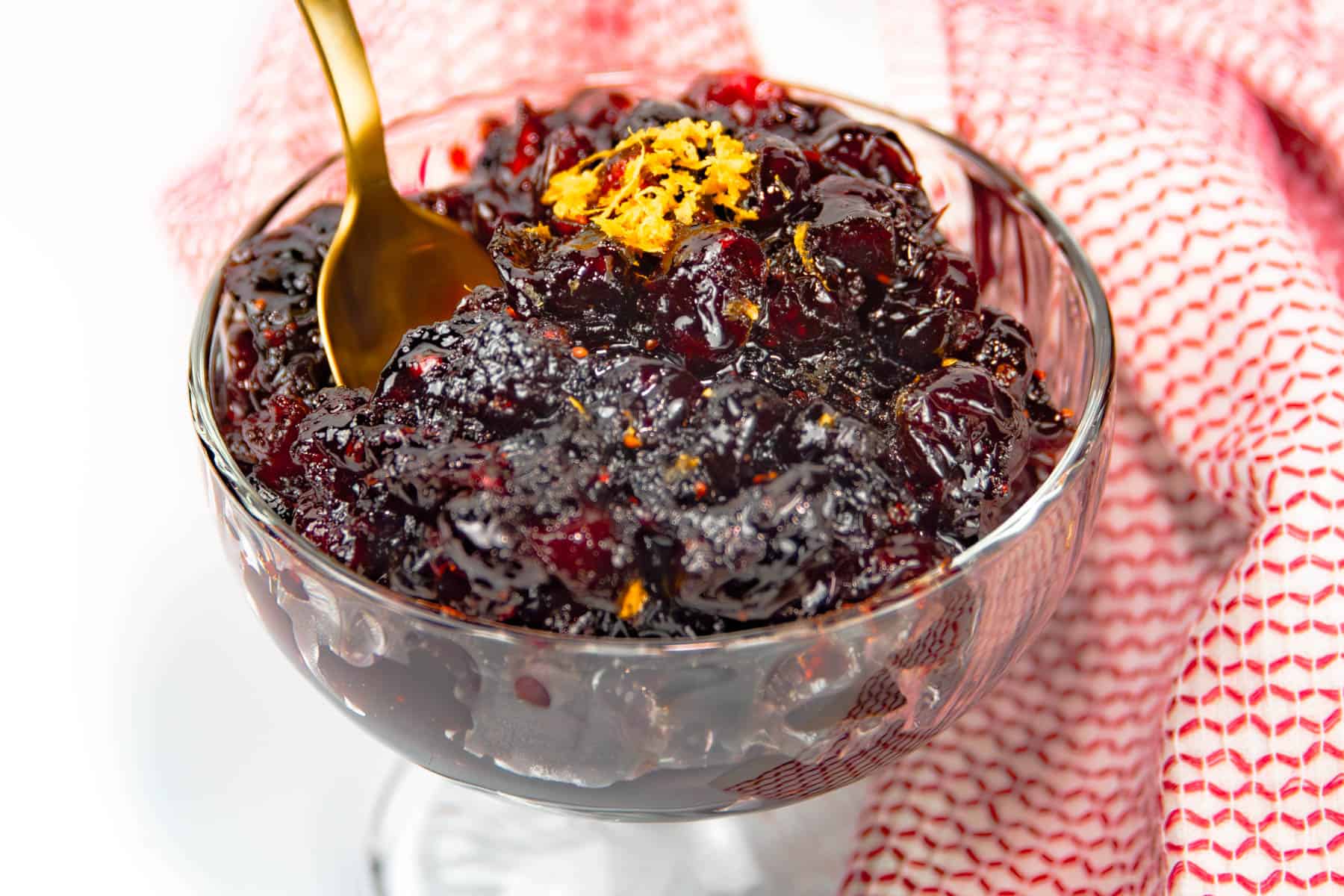 Cranberry sauce in a glass bowl with a spoon.