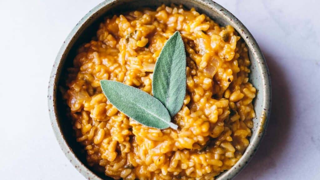 A bowl of pumpkin risotto with sage leaves.