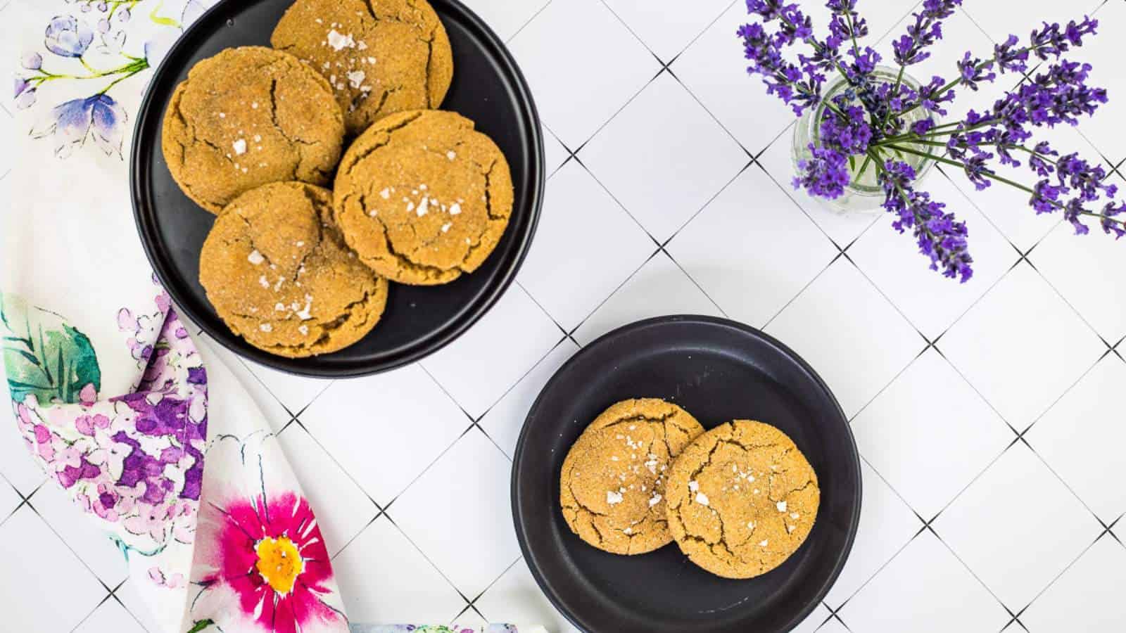 Two bowls of salted caramel snickerdoodle cookies on a plate with lavender flowers on the table.