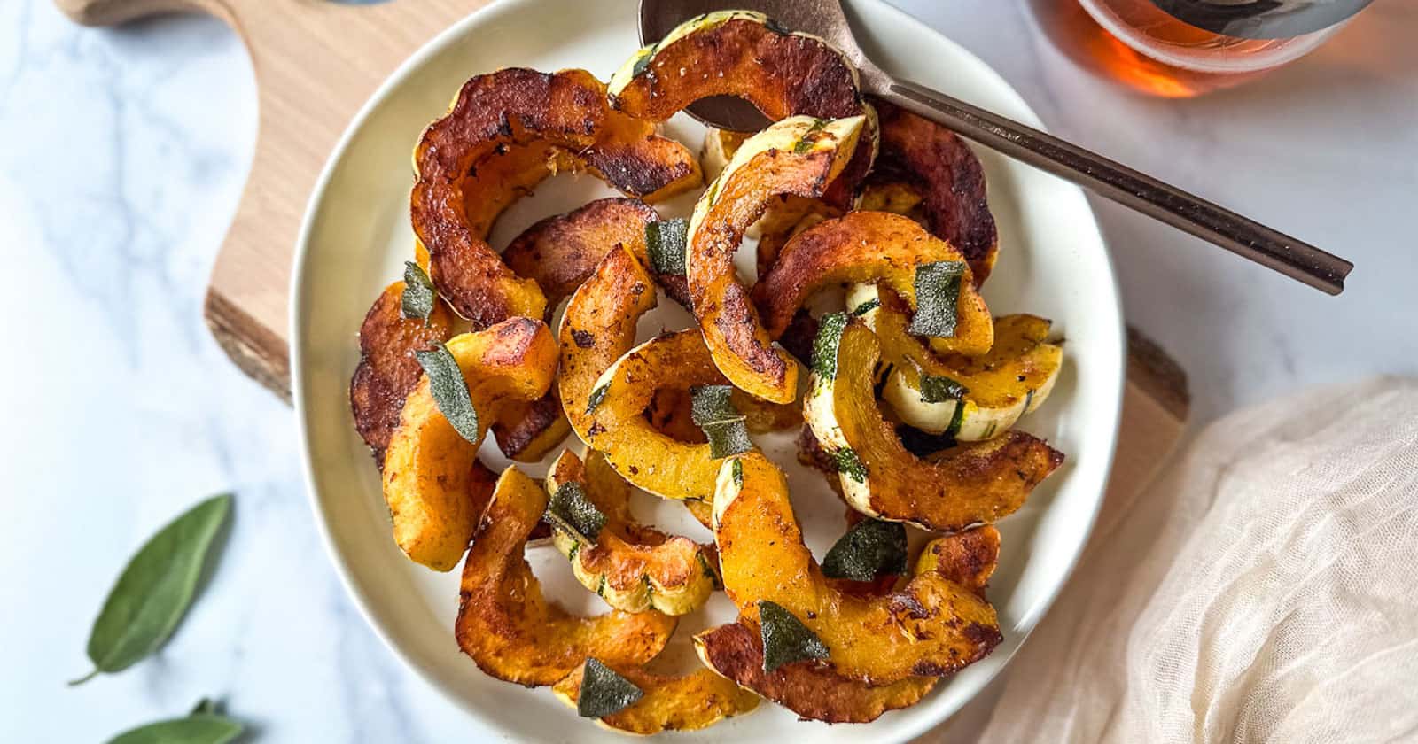 Sautéed delicata squash on a white plate with fried sage.