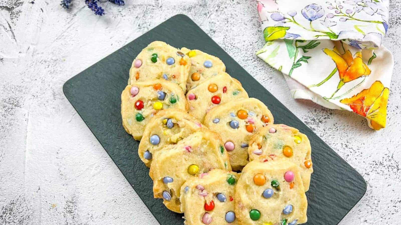 Shortbread M&M cookies on a black plate with flowers.