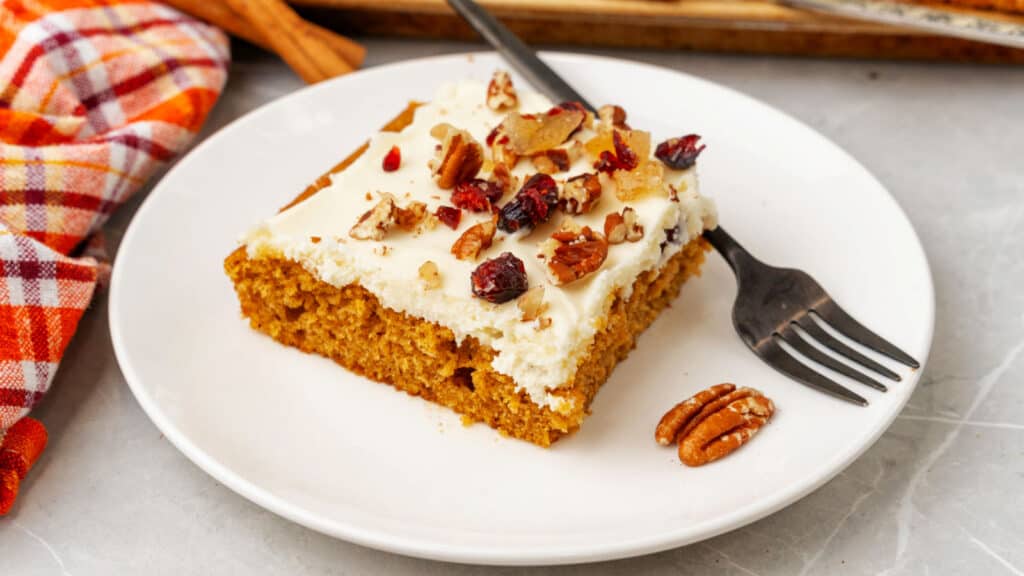 A slice of pumpkin cake on a plate with a fork.