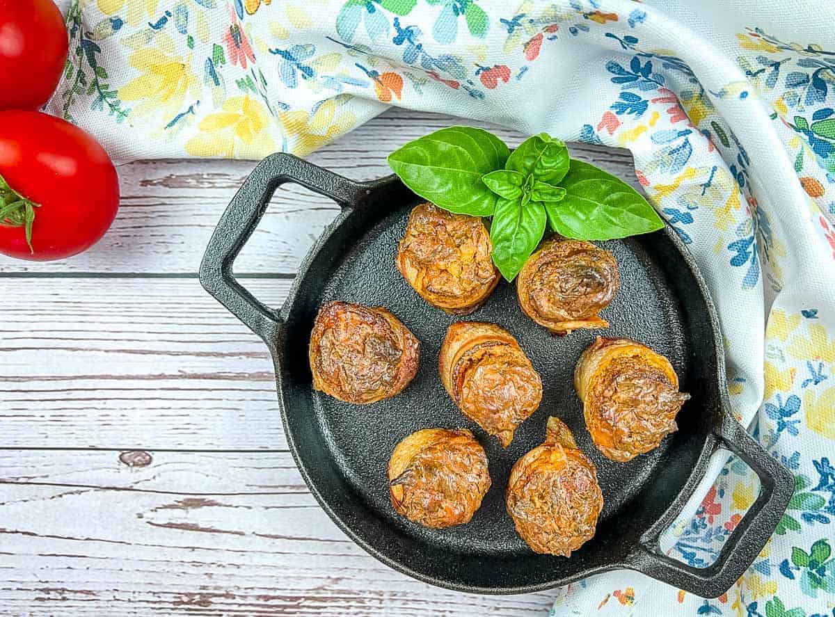 Smoked pork shots in a skillet with basil and tomatoes.