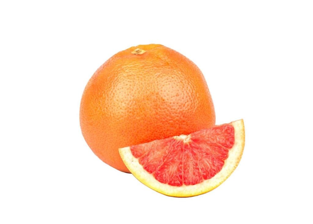 A grapefruit, one of the winter fruits, is cut in half on a white background.