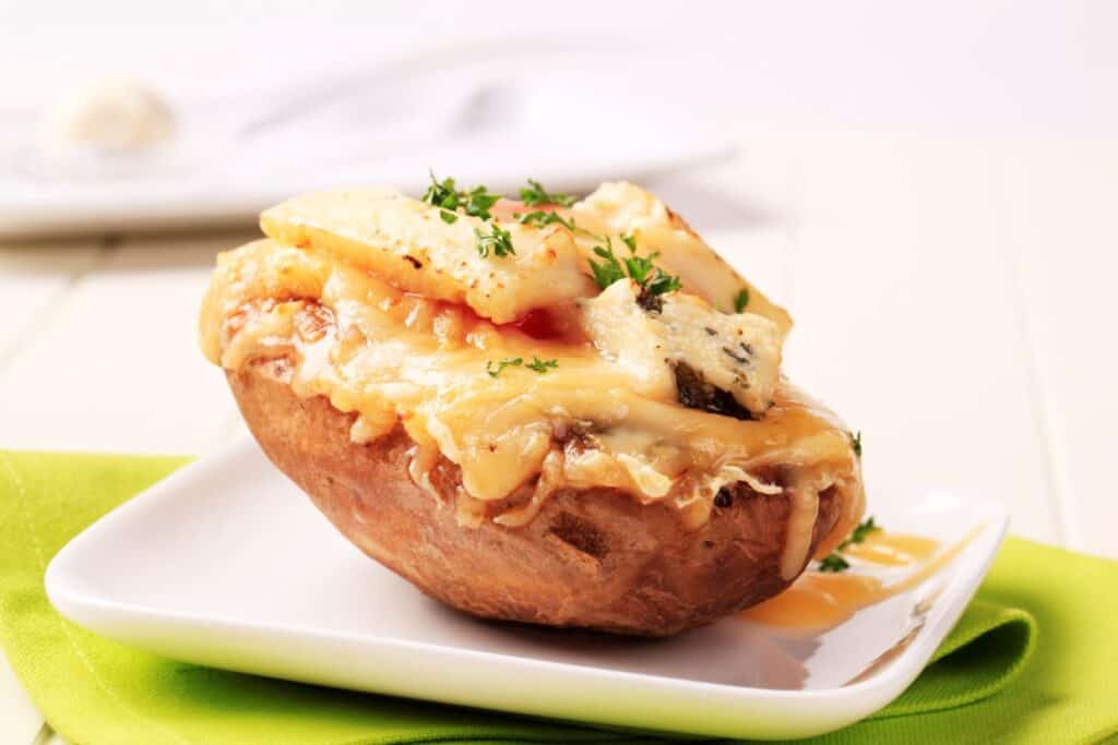 A baked potato topped with aged cheese and herbs.