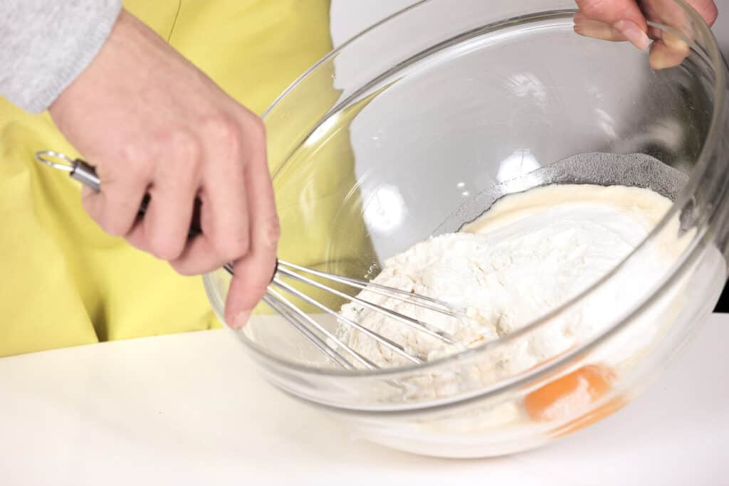 A person whisking together the ingredients in a batter.