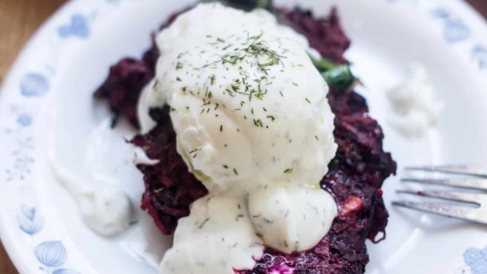 Beetroot pancakes with sour cream on a plate.