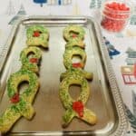 A tray of christmas cookies with green ribbons on it.