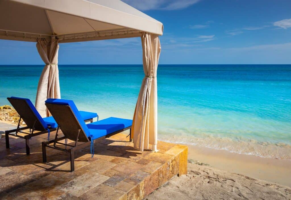 Two lounge chairs on a beach in the caribbean.