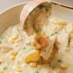 A bowl of chicken pot pie soup being scooped with a spoon.