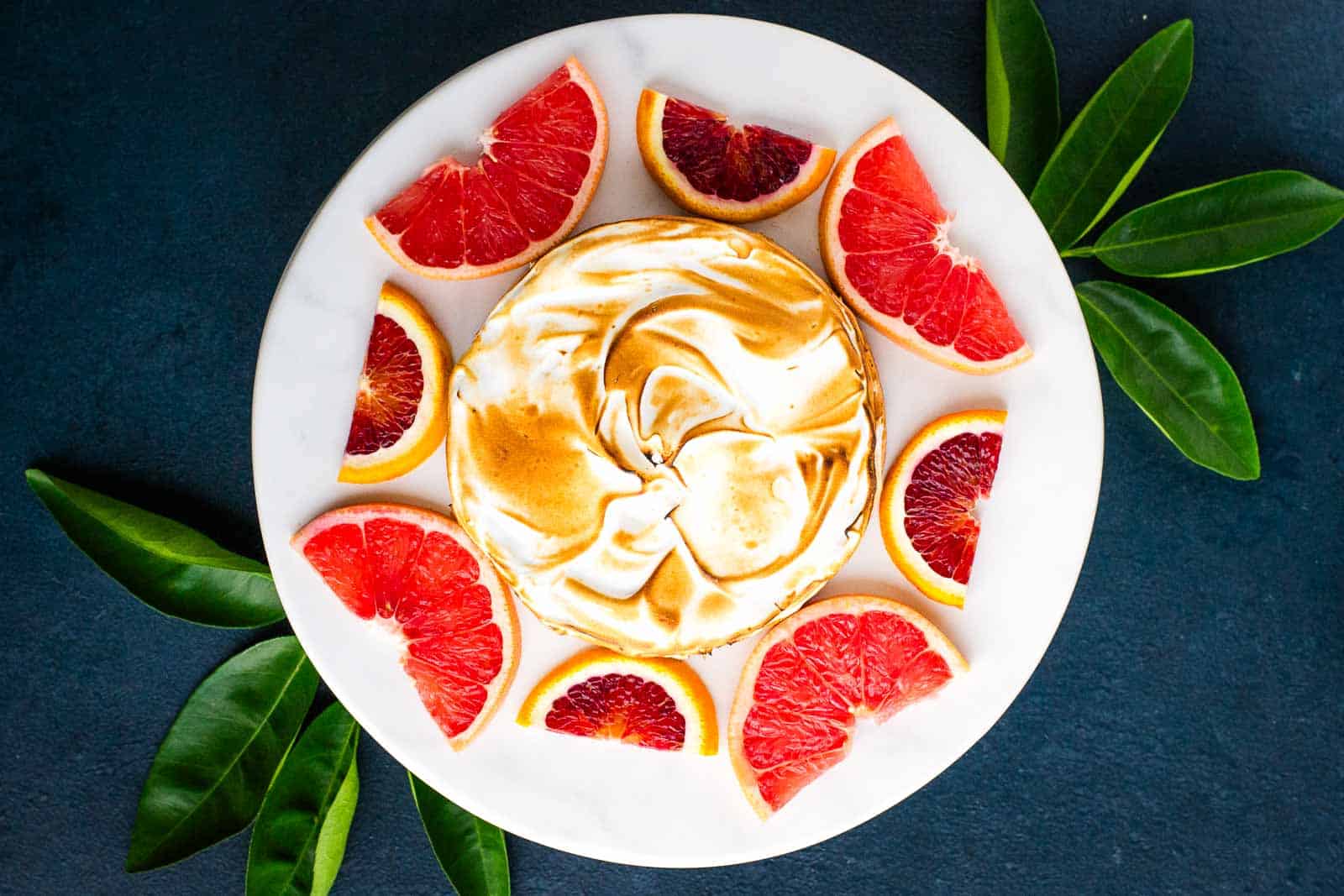 A plate with Citrus Dream Tart next to slices of grapefruit and blood orange.