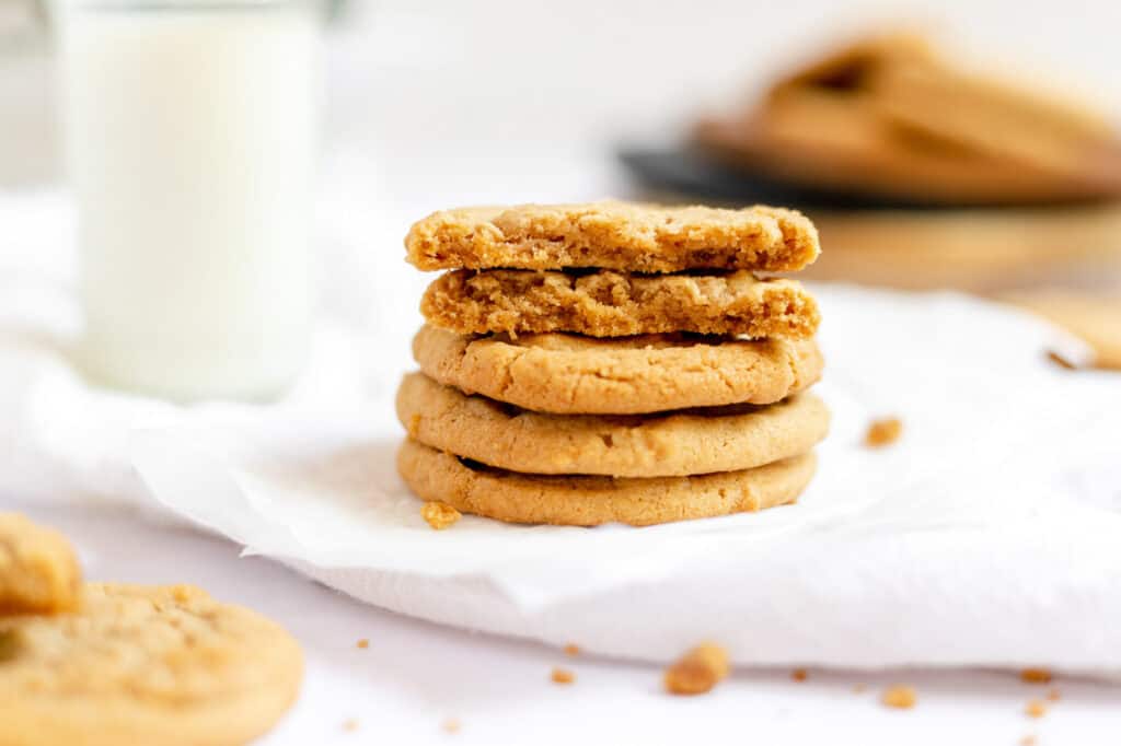 A stack of cookie butter cookies next to a glass of milk.