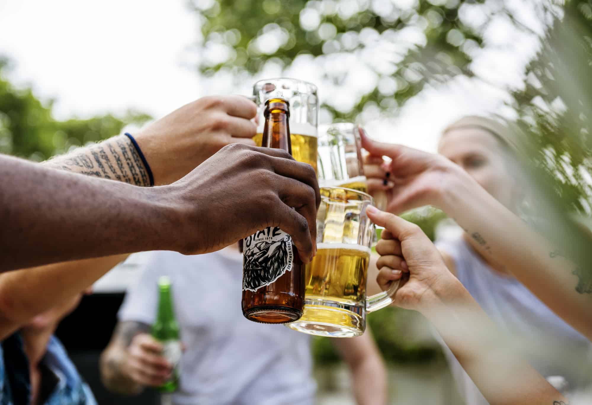 A group of people toasting beer bottles outdoors.
