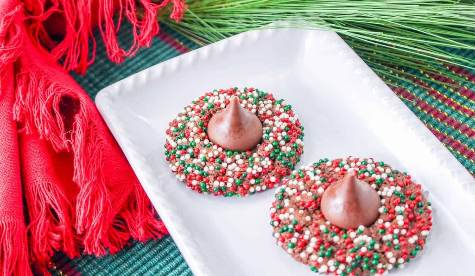 Two chocolate blossom Christmas cookies on a white plate.