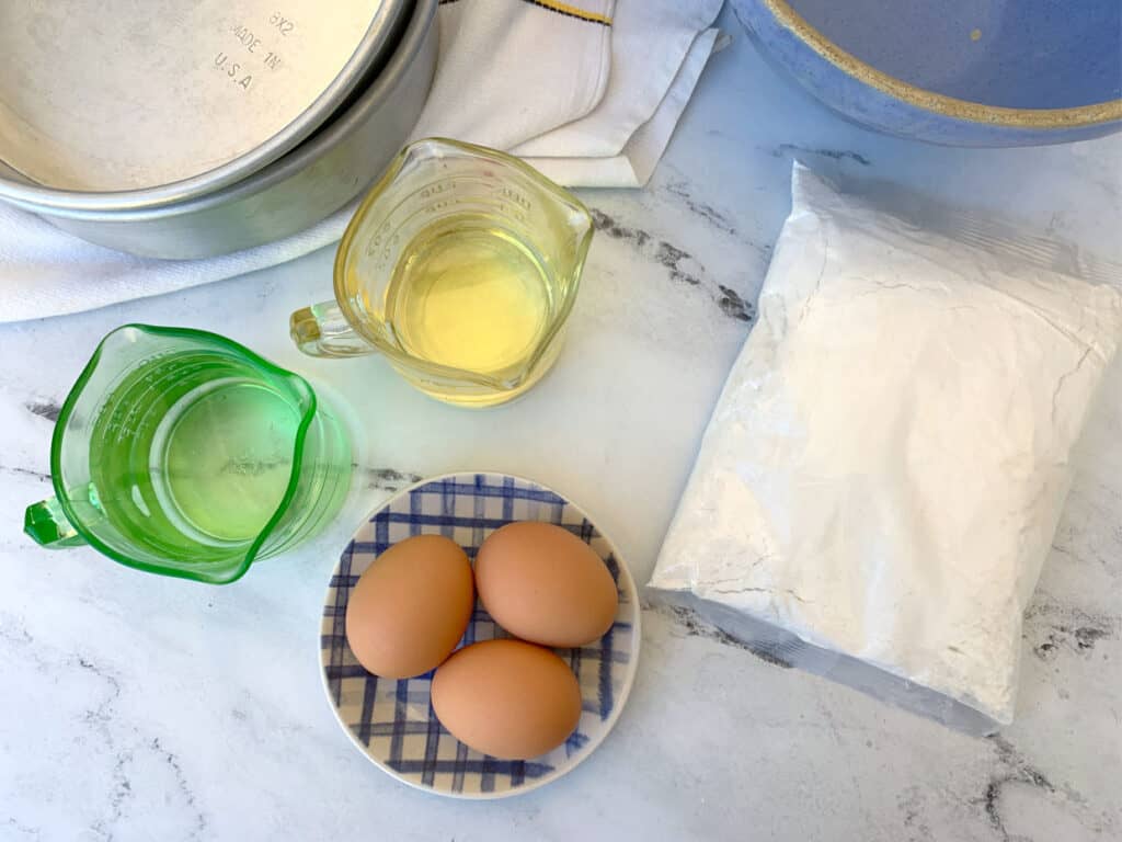 A bowl of eggs, flour and other ingredients on a marble counter.