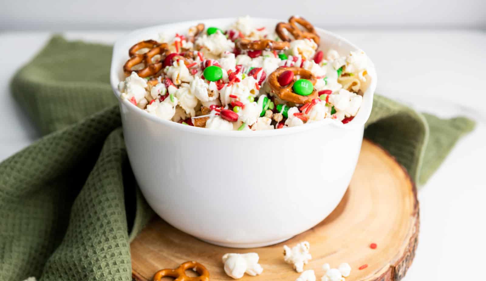 Christmas popcorn in a white bowl with pretzels.