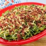 Green beans with bacon and almonds on a red plate.