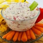 A bowl of dip with carrots and celery.