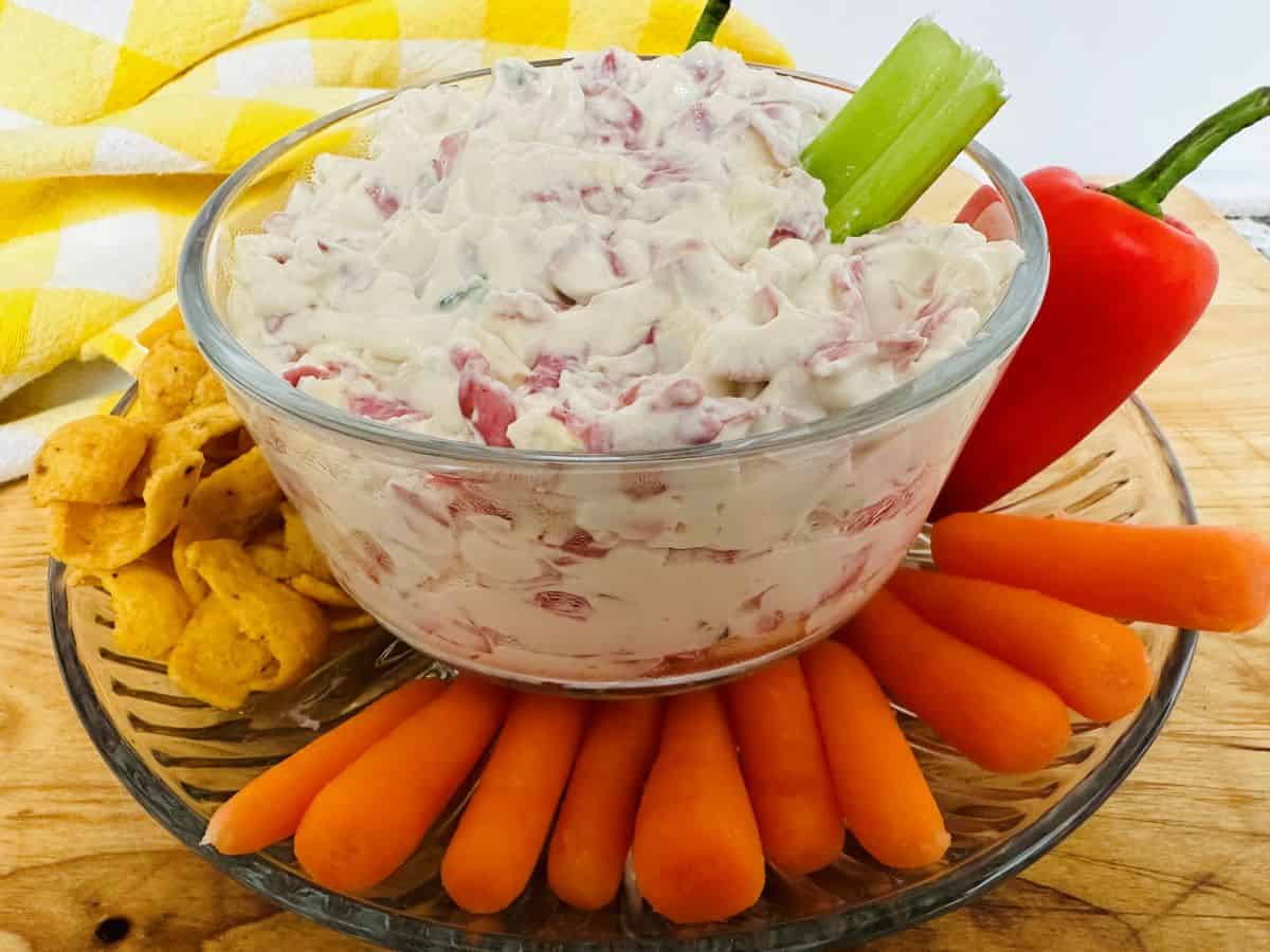 A bowl of dip with carrots and celery.