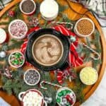 A wooden platter with hot cocoa, candy canes, and marshmallows.