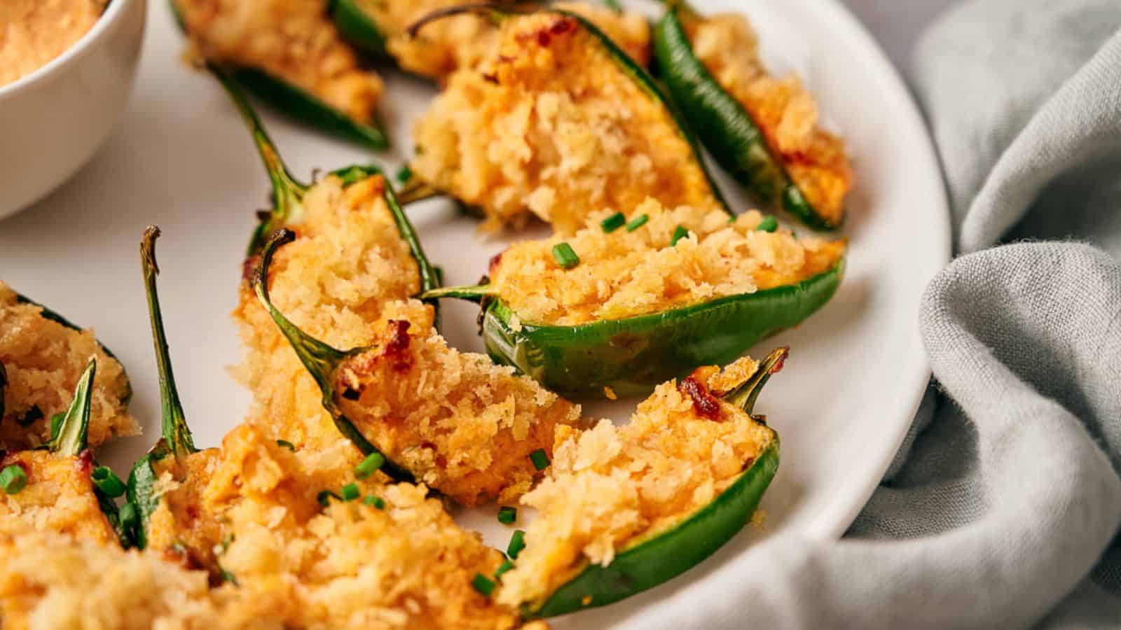 Baked jalapenos on a plate with dipping sauce.