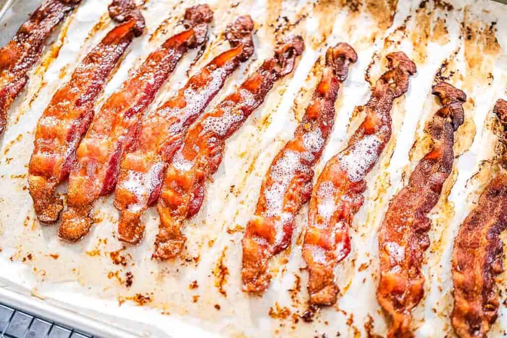 Thin-sliced oven-baked bacon on a baking sheet.