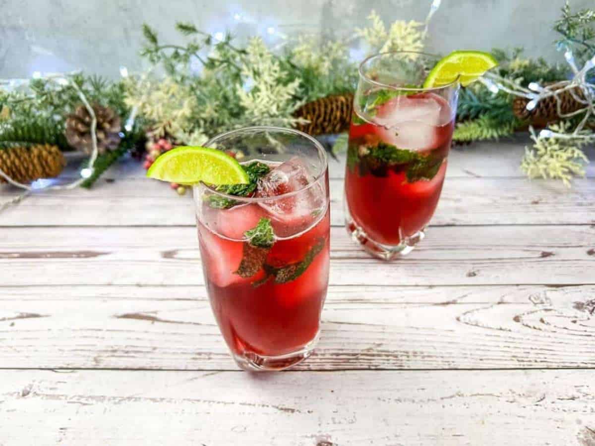 Two pomegranate mojito mocktails with a lemon on top of it.
