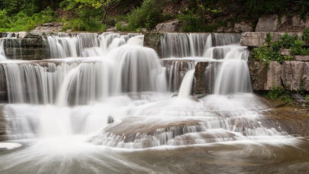 A waterfall in the middle of a wooded area.