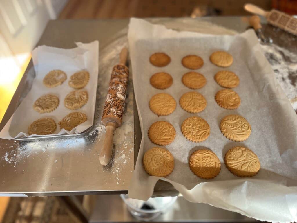 A tray of cookies on a table next to an embossed rolling pin.