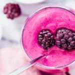 A pink smoothie with blackberries and bananas.