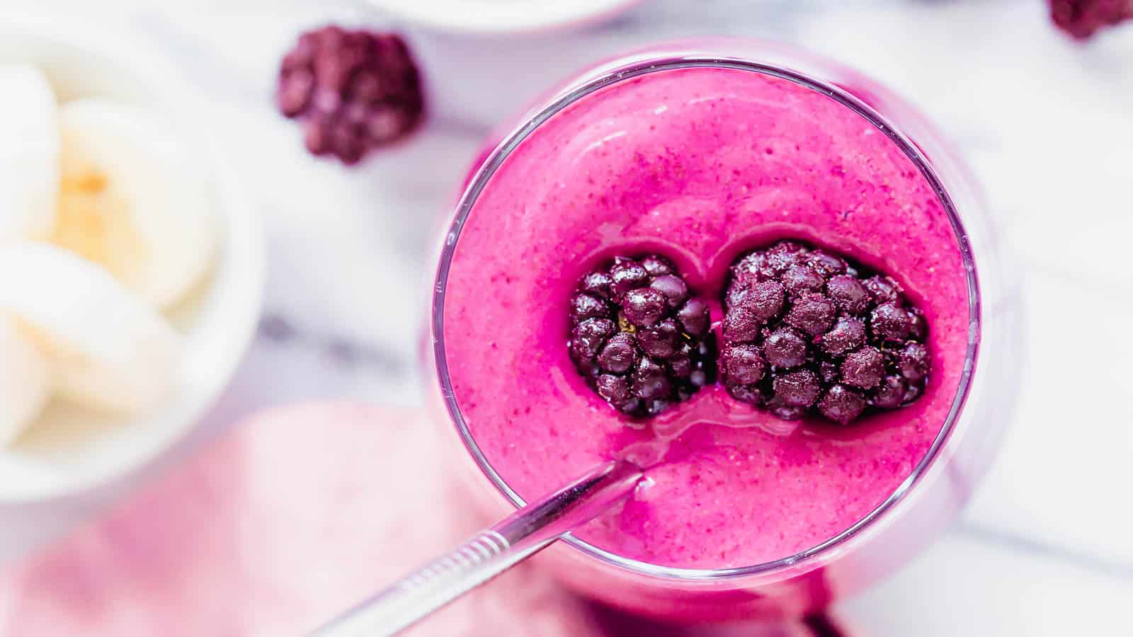 Blackberry smoothie recipe in a glass topped with frozen blackberries.