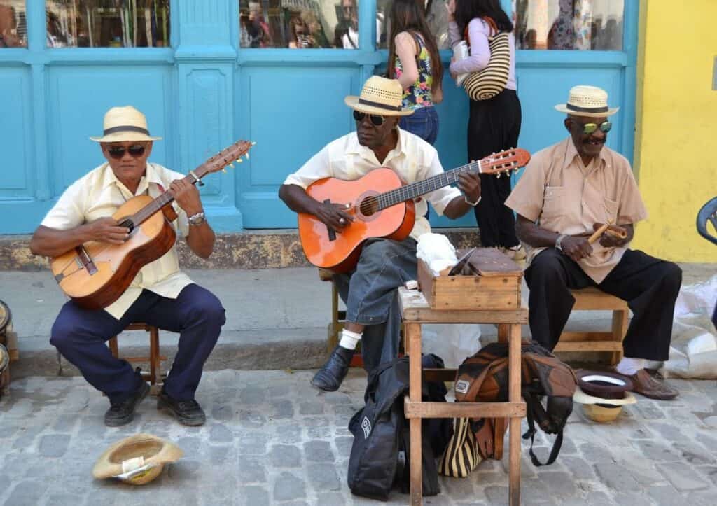 A group of men playing guitars on a cobblestone street.