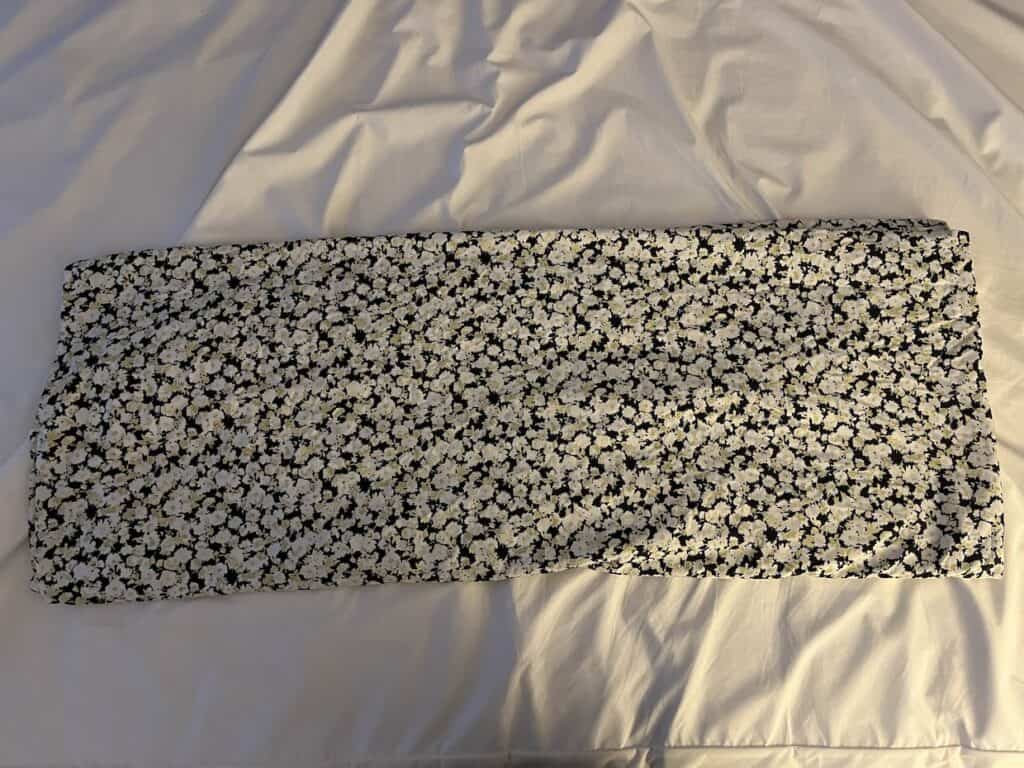 A white and black pillowcase on a bed, demonstrating how to fold a fitted sheet.