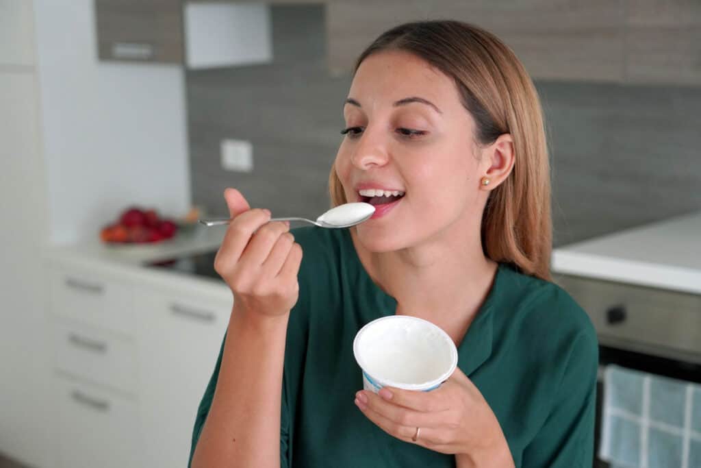 A woman enjoying a healthy yogurt snack in her kitchen.