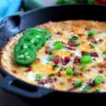 A skillet filled with a baked jalapeno popper dip.