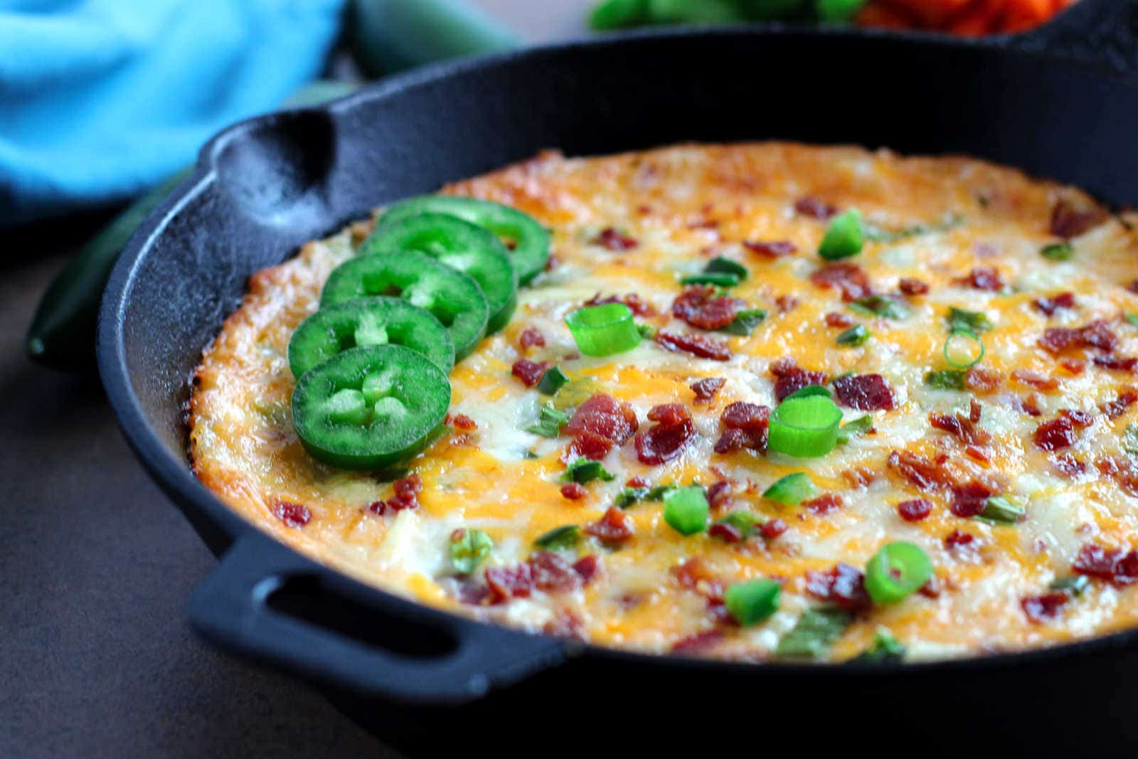 A skillet filled with a baked jalapeno popper dip.