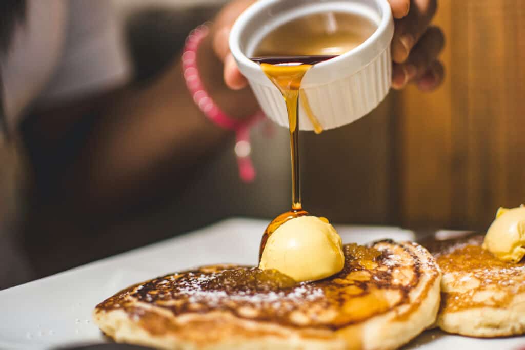 A person is pouring syrup onto pancakes.