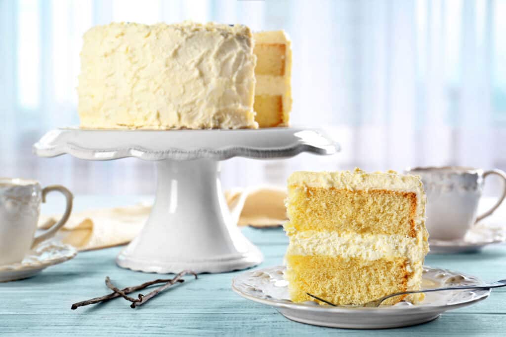 A slice of yellow cake on a white plate.