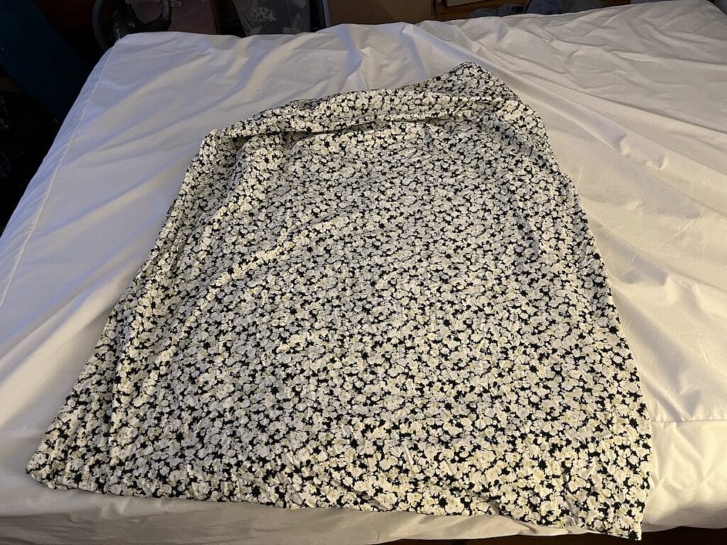 A white and black blanket on top of a bed and how to fold a fitted sheet.
