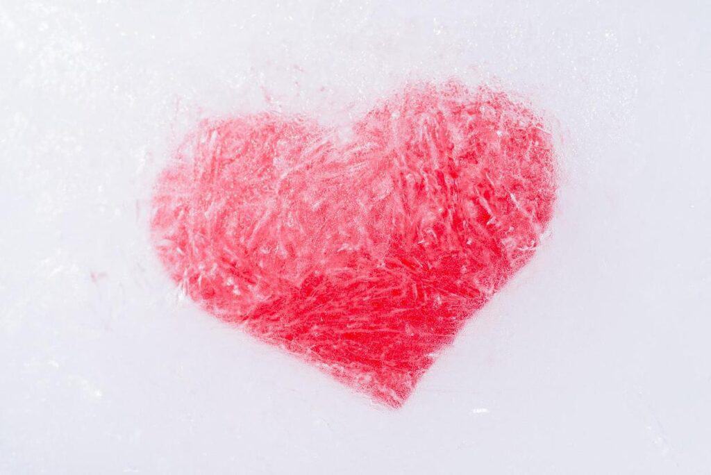 A red heart is shaped out of snow.