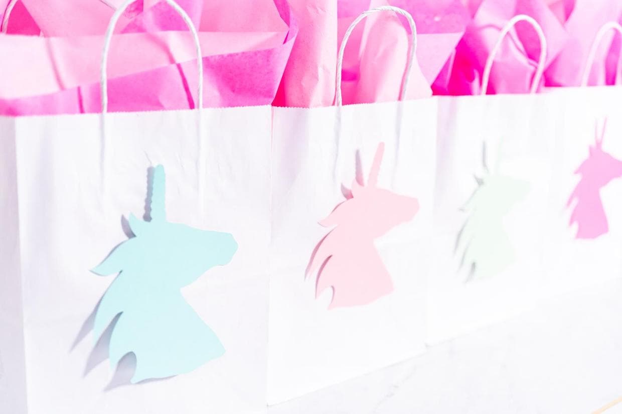 A group of pink and blue paper goodie bags with unicorns on them.
