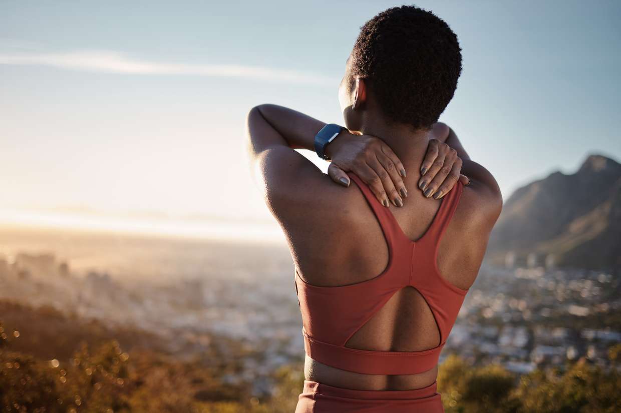 A woman practices wellness tips by stretching her back while looking at the city.