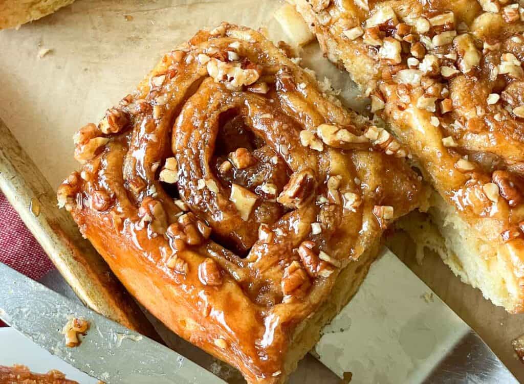 Cinnamon rolls with pecans on a cutting board.
