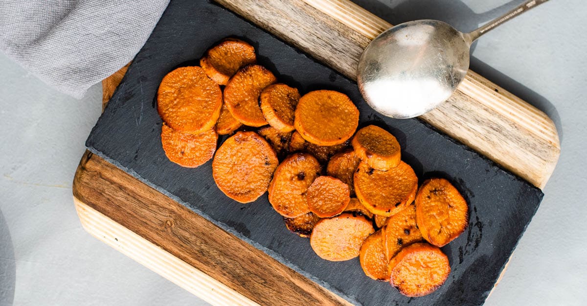 Baked sweet potato slices on a cutting board with a spoon.