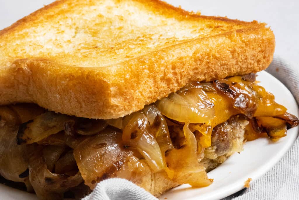 A grilled sandwich with onions and cheese on a plate.