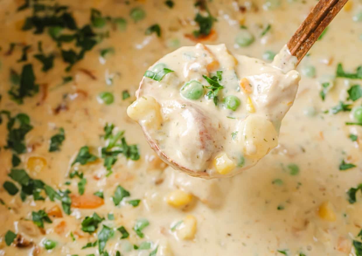 Chicken pot pie soup in a white bowl with a spoon.