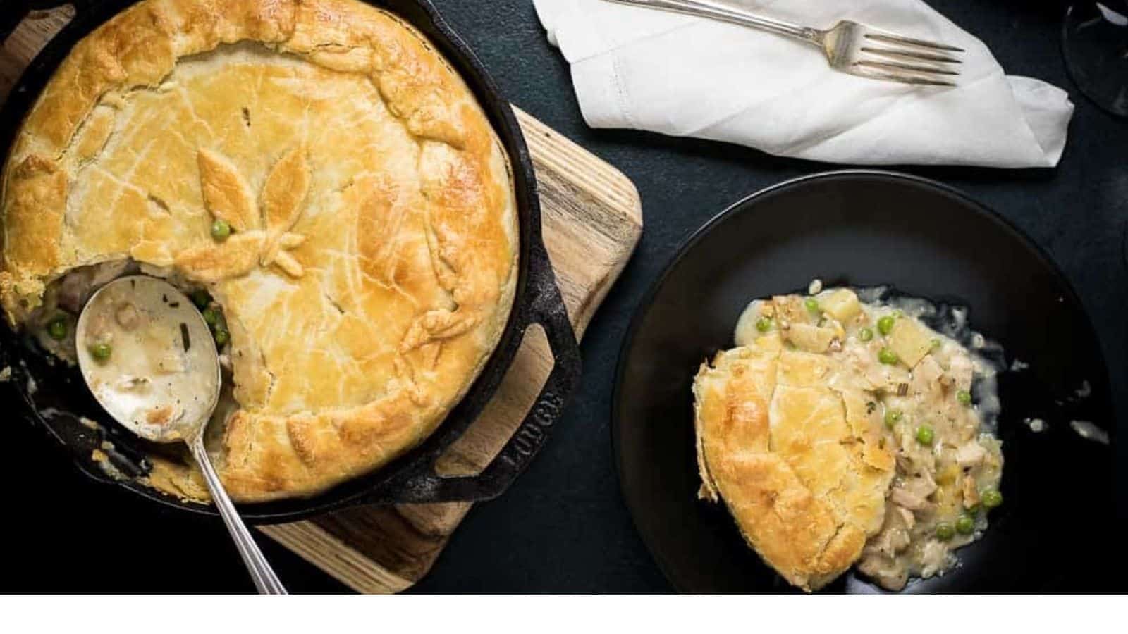 A chicken pot pie on a plate with a spoon next to it.