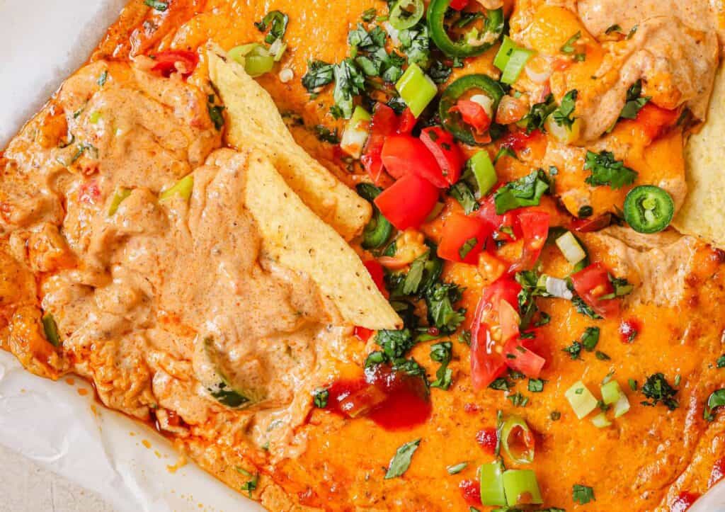 Chili cheese dip in a baking dish with toppings.