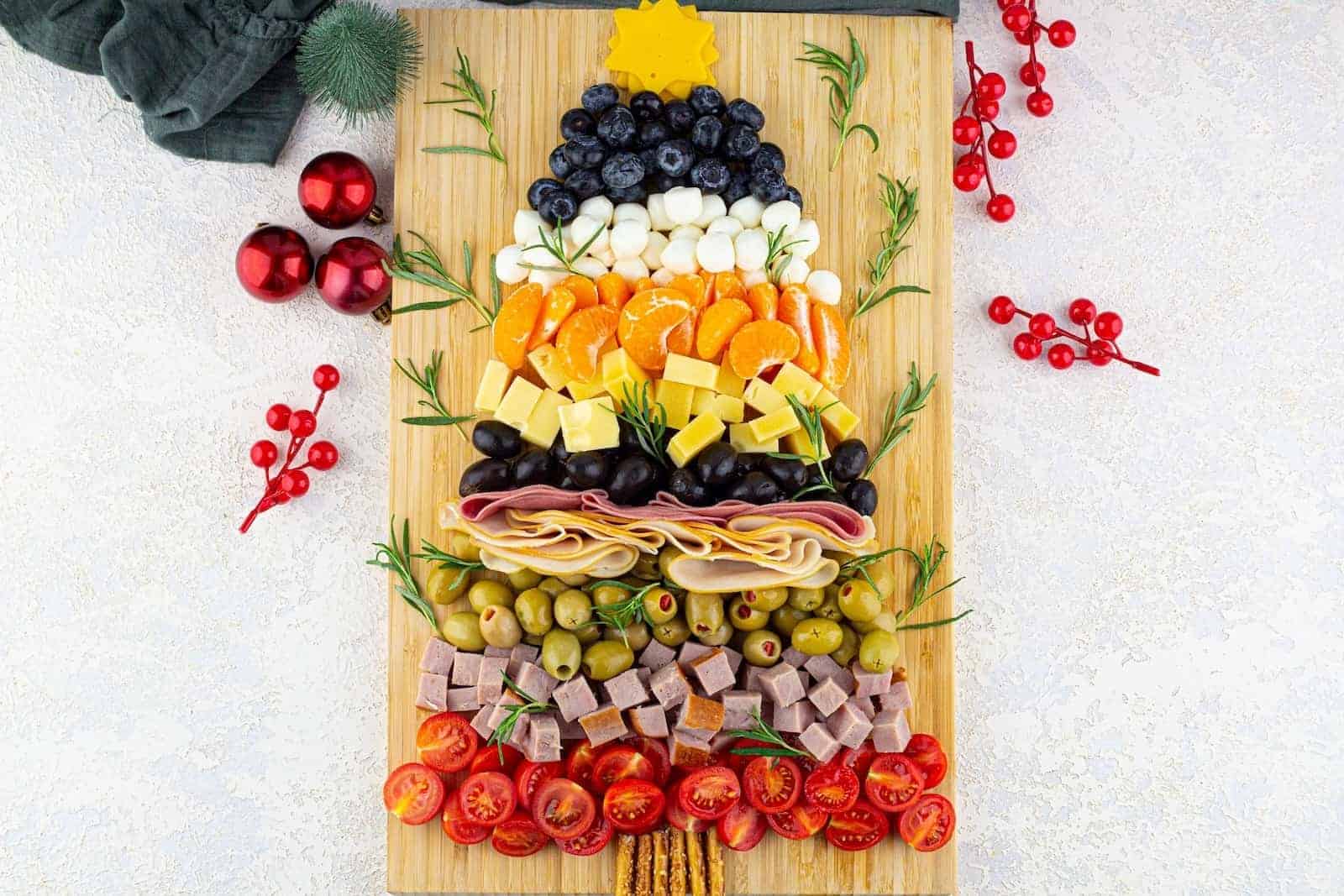 A Christmas tree charcuterie board made of cured meat, cheese, olives, and fruit.
