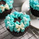 Christmas wreath cupcakes decorated with blue frosting on a cooling rack.